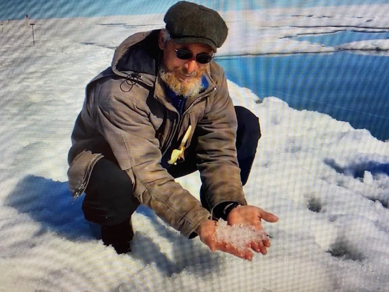 During a 2019 snow-sampling excursion in the North Slope of Alaska, Matthew Sturm scoops up icy snow near a springtime melt pond. YouTube screengrab from a video by the Geophysical Institute, University of Alaska Fairbanks.