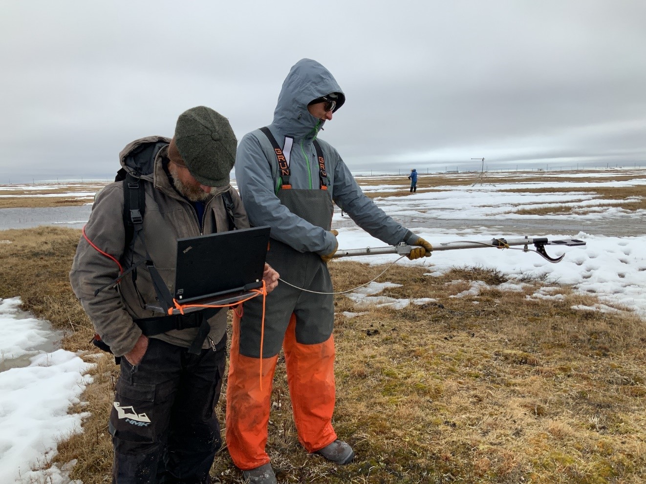 Sturm, left, studies a computer readout during SALVO work in the spring of 2019. Dark patches of tundra emerge to soak up more heat, decreasing the albedo of the landscape.