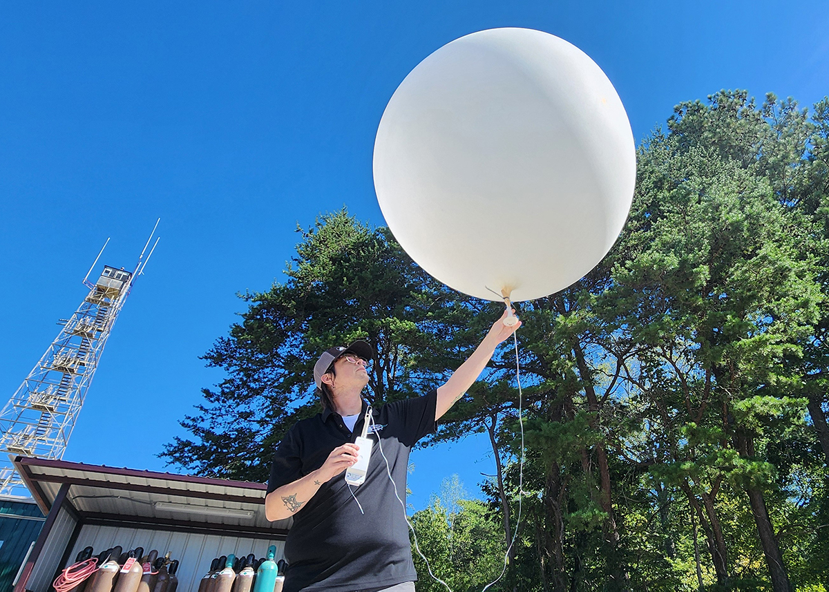 On September 18, 2024, technician Kris Bennefield prepares to launch a weather balloon with a radiosonde attached at the main site of ARM’s Bankhead National Forest (BNF) atmospheric observatory near Moulton, Alabama. Bennefield and other BNF staff are working toward the official start of data collection on October 1. 