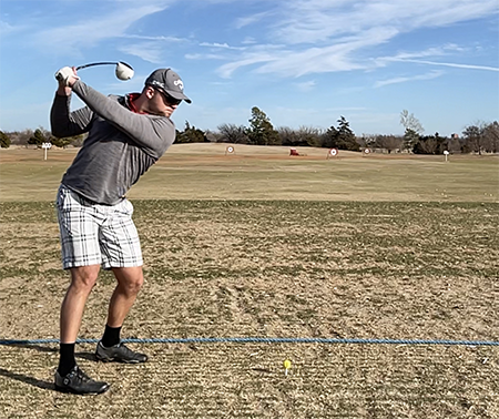 Aiming for the clouds at the Westwood Park driving range in Norman, Oklahoma, Dzambo winds up with during early-season golf practice in February 2023.