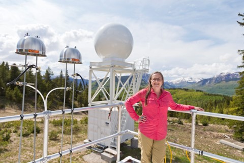 In June 2023, SAIL co-investigator Allison Aiken pauses next to ice-nucleating particle samplers on Crested Butte Mountain. Behind her is an X-band precipitation radar from Colorado State University. Photo is by Bilow.