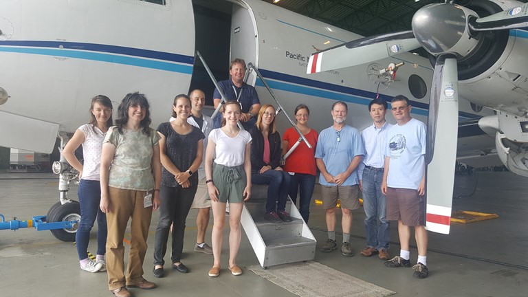 In July 2017, the team of scientists and technicians working on Aerosol and Cloud Experiments in the Eastern North Atlantic (ACE-ENA) gather in a hangar on Teixeira Island in the Azores for a group photo. Wang, who led the ARM field campaign, is second from right.